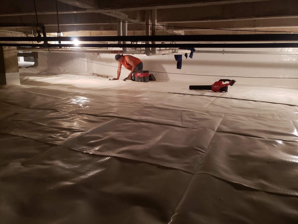 Worker Performing Crawl Space Encapsulation with Tools
